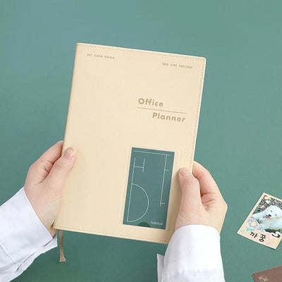 Office Planner ICONIC Ivory with flexible PVC cover and 192 pages, shown in hand.