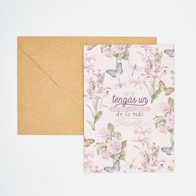 Tarjeta de felicitación de cumpleaños con diseño floral, mariposas y libélulas, junto a sobre kraft.