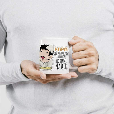 Taza Papá Huevos con diseño divertido y mensaje simpático en manos de persona, ideal para regalar y alegrar las mañanas.